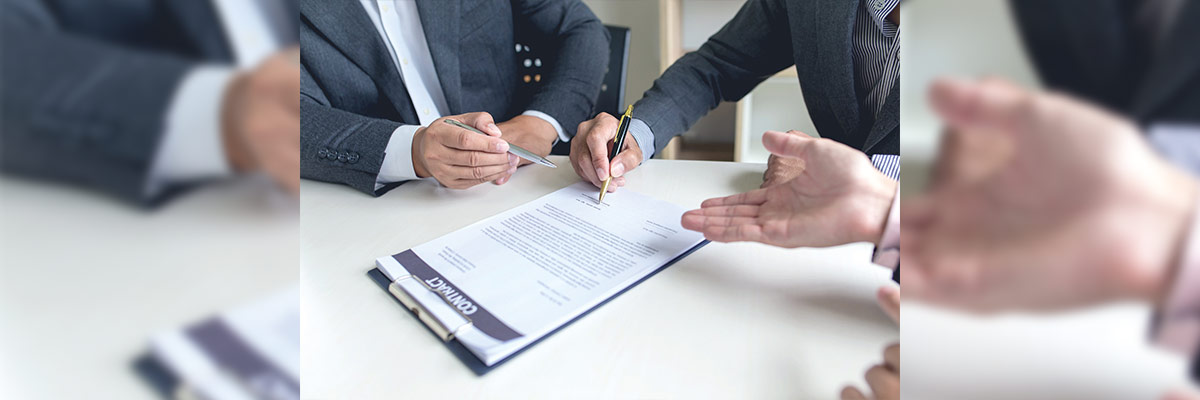 Captura del momento en que dos individuos firman un documento, simbolizando un acuerdo profesional