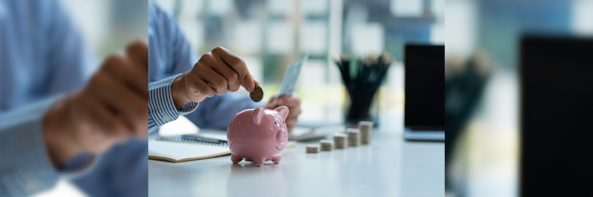 Ahorro Una persona depositando una moneda en una hucha en forma de cerdito, simbolizando el acto de ahorrar e invertir de manera consciente