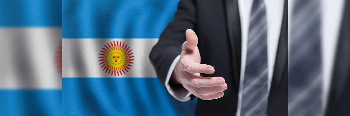 Mano extendida en gesto de acuerdo. La escena se vuelve aún más significativa por el fondo que adorna esta interacción: la bandera argentina