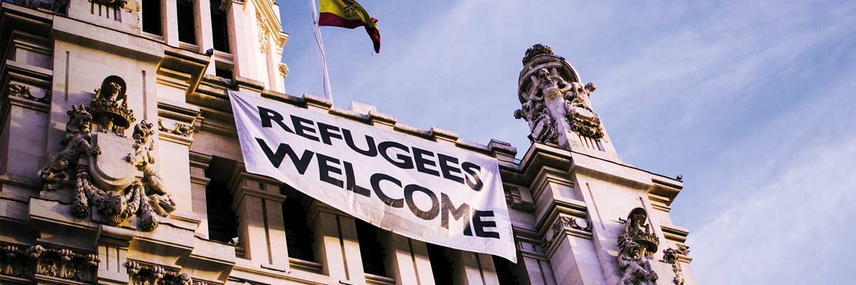 Edificio de correos. Ayuntamiento de Madrid con la bandera de bienvenidos refugiados