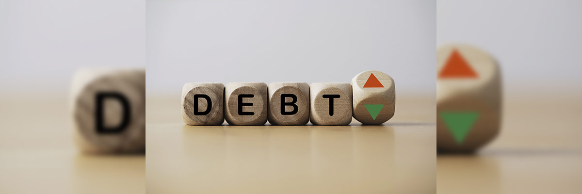Cubos de madera con la palabra ‘DEBT’ y un cubo adicional con flechas hacia arriba y hacia abajo, simbolizando las fluctuaciones y el manejo de la deuda