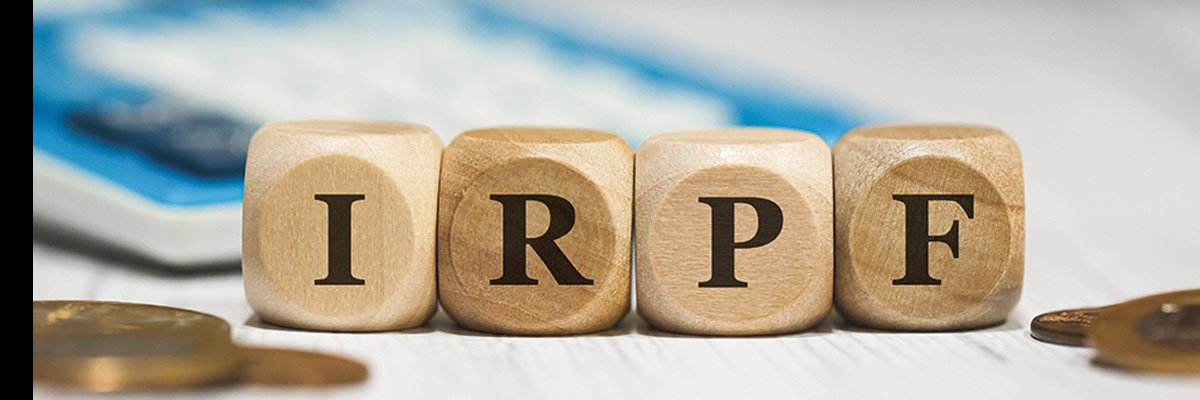 declaración de la renta Bloques con letras "IRPF" junto a monedas y calculadora, símbolo de la declaración y gestión del impuesto sobre la renta.