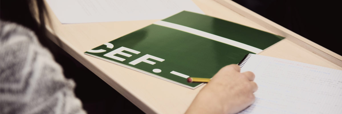 Estudiante escribiendo en un cuaderno y al lado una carpeta del CEF.- 
