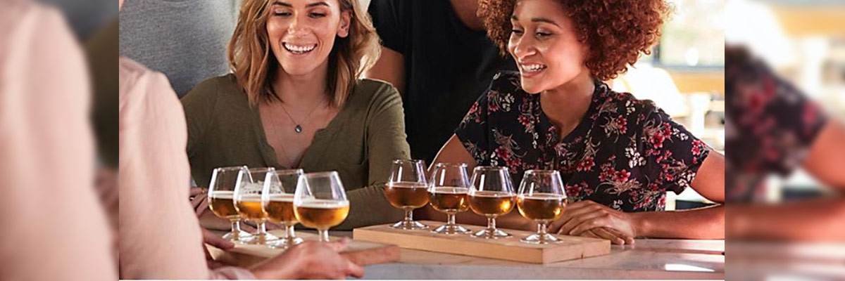 Un grupo de personas disfrutando de una degustación de cervezas, con varias copas de cerveza dispuestas en bandejas de madera.