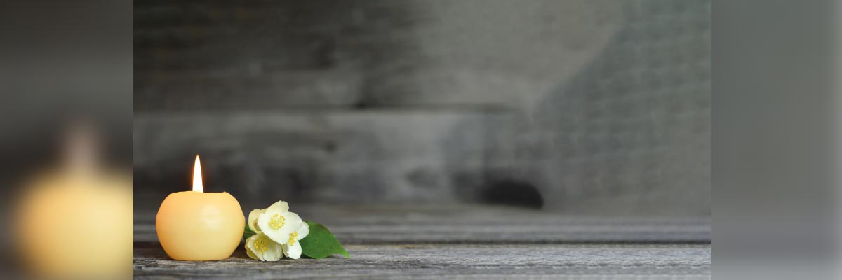 Vela encendida al lado de unas flores blancas Vela encendida al lado de unas flores blancas