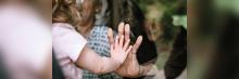 Anciana y niña unen sus manos a través de un cristal