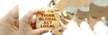 Pensar globalmente actuar localmente Mano sujetando una pieza de manera donde dice pensar globalmente actuar localmente