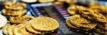 Monedas de bitcoin apiladas sobre una pantalla que muestra gráficos de cotizaciones