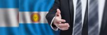 Mano extendida en gesto de acuerdo. La escena se vuelve aún más significativa por el fondo que adorna esta interacción: la bandera argentina
