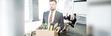 Despido en la oficina Empleado sale de la oficina con caja de pertenencias tras un despido; imagen sobre despido y transición laboral.