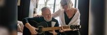 Música y mindfulness para mayores Persona mayor toca la guitarra guiada por terapeuta; música y mindfulness para prevenir la soledad.