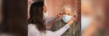 Chica con mascarilla ajustando la mascarilla a una persona de avanzada edad